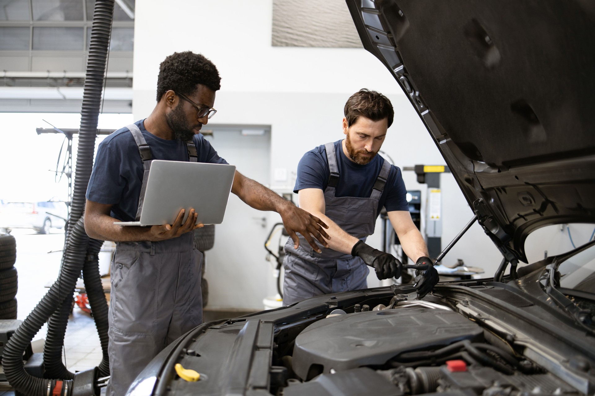 Dos mecánicos trabajando en el motor de un coche en el garaje