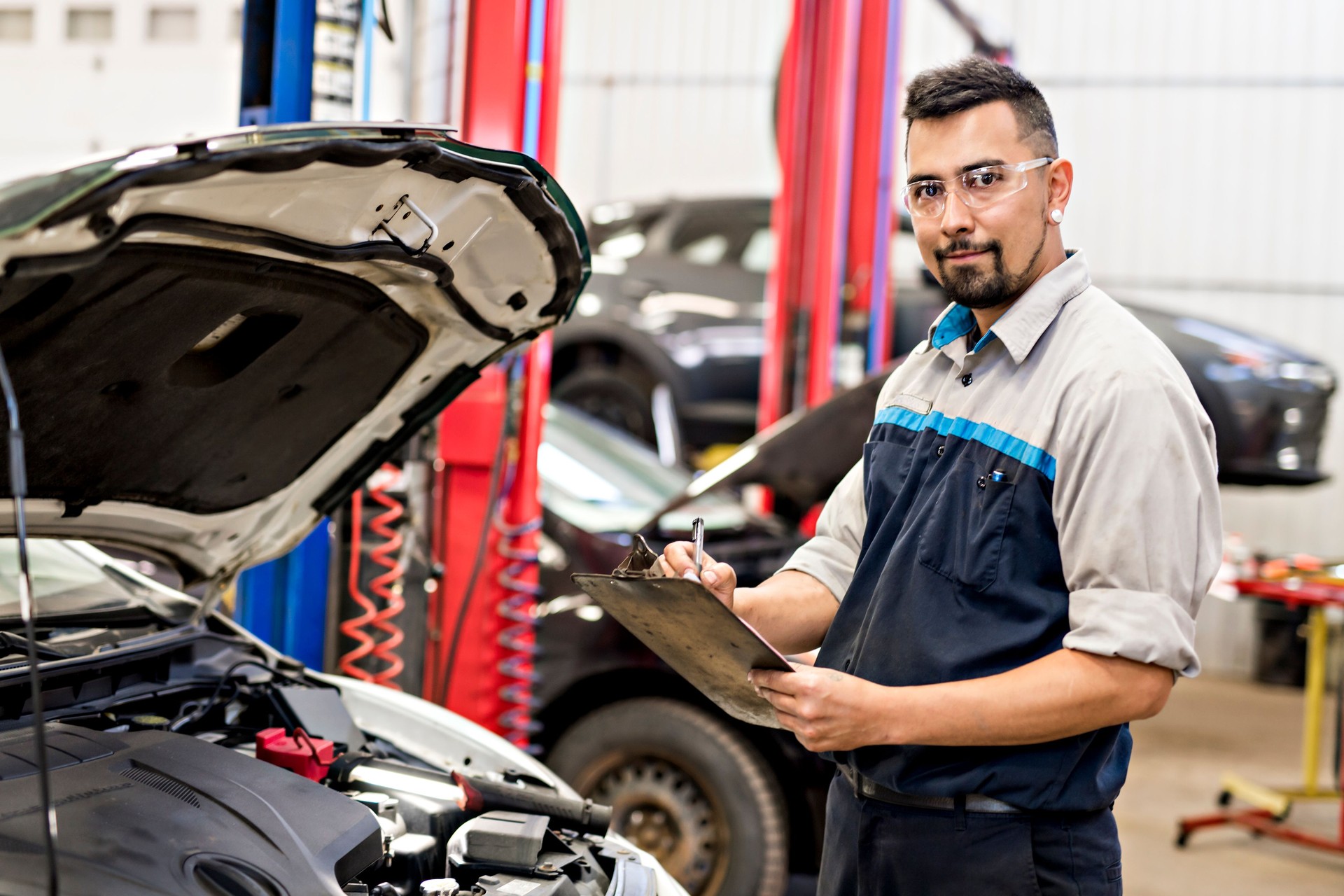 Hermoso trabajo mecánico en uniforme trabajando en coche