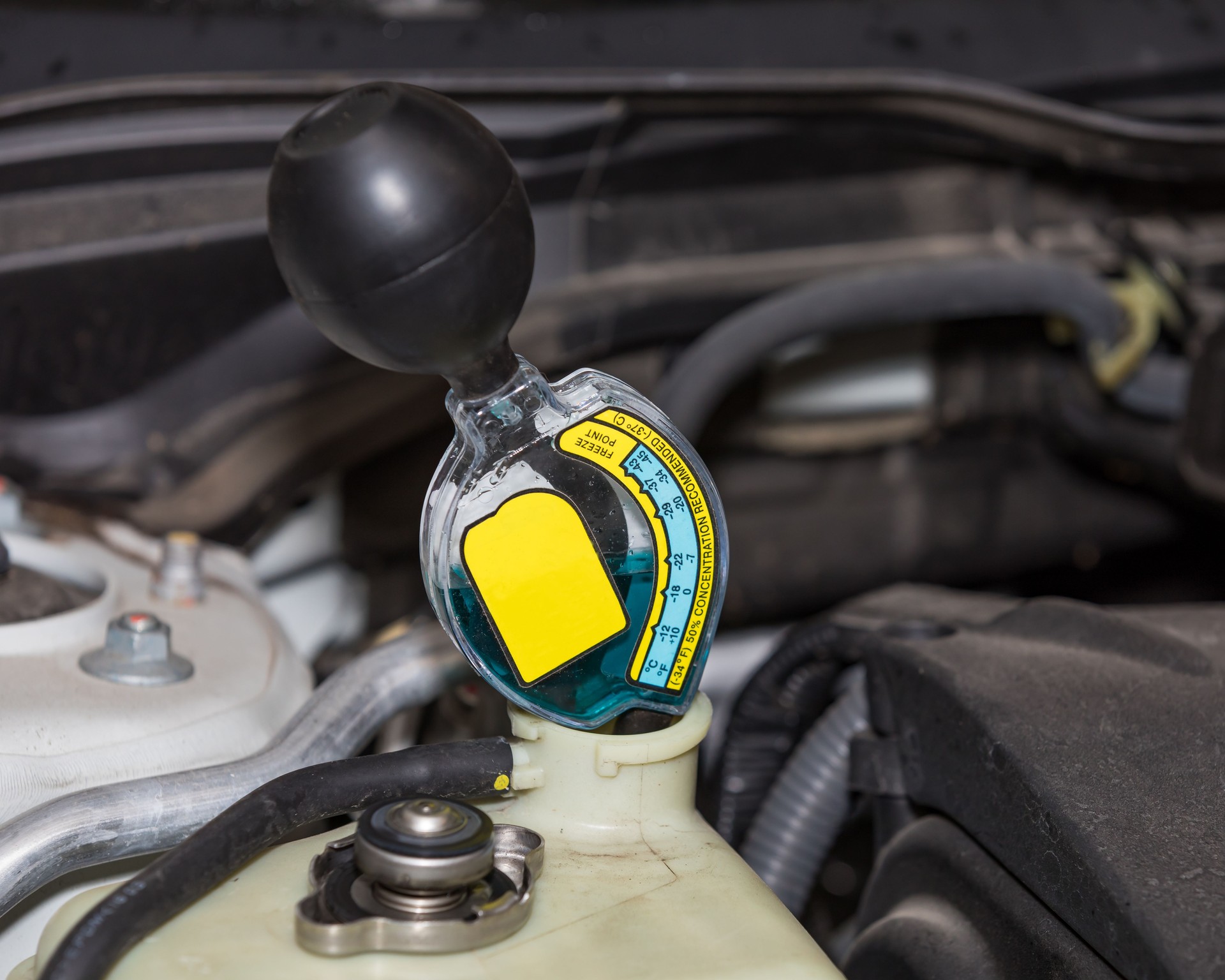 Probador anticongelante que comprueba la protección contra congelación del líquido refrigerante en el tanque de recuperación de expansión de plástico para el radiador en un sistema de refrigeración de automóvil. Concep de mantenimiento de coches de