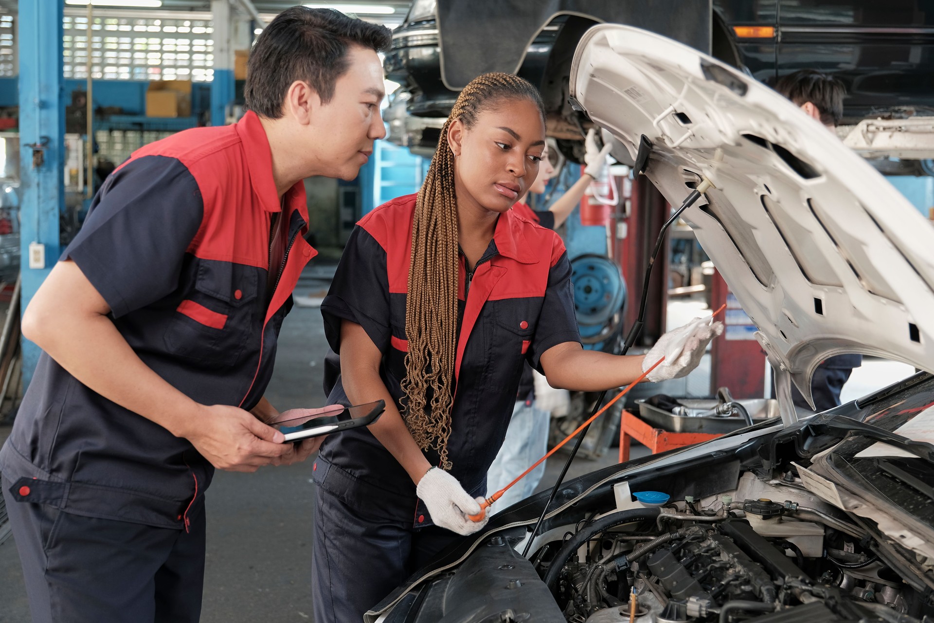 Un supervisor automotriz y una mecánica negra trabajan en un garaje de automóviles.