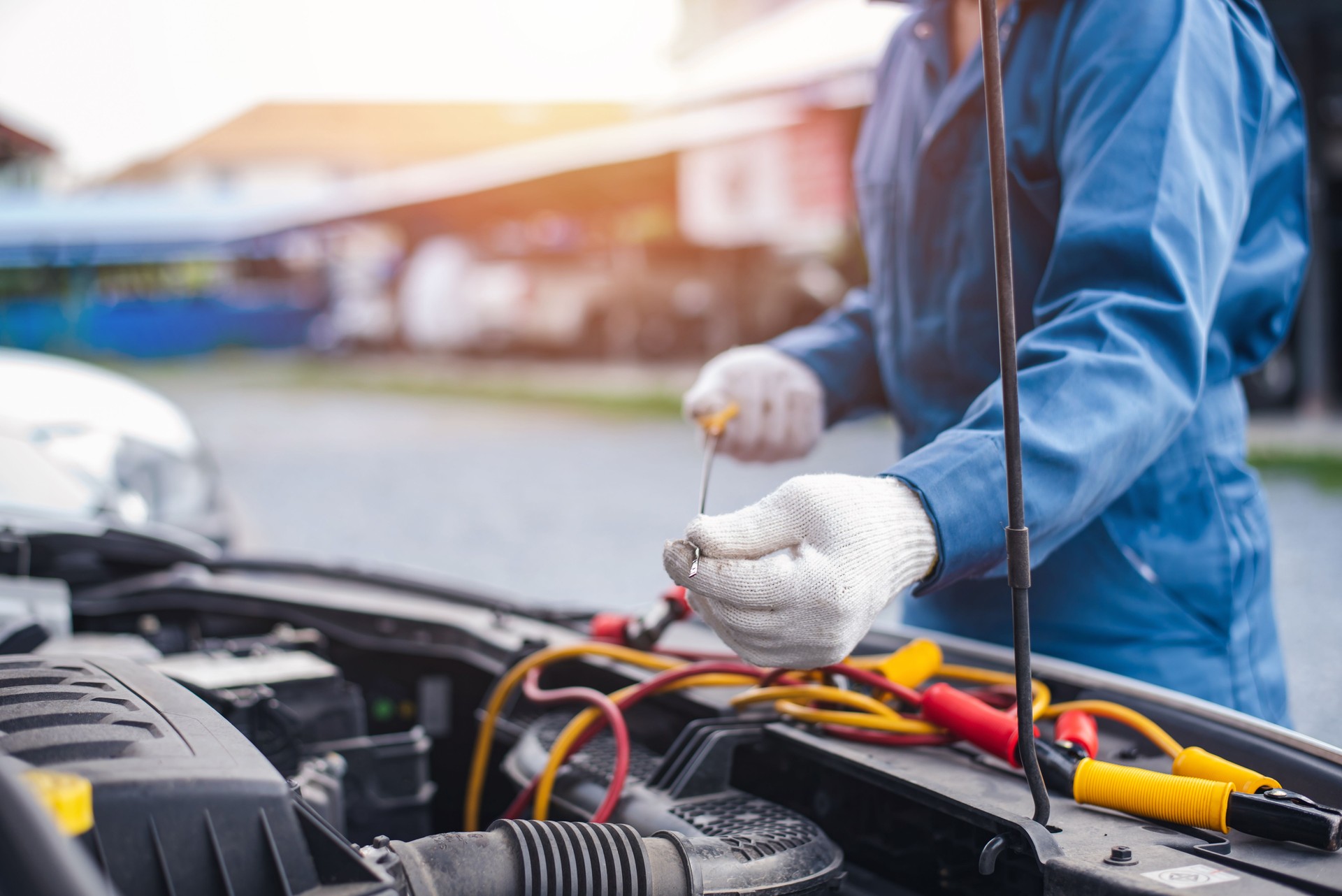 Mecánico revisando el nivel de aceite en el motor de un automóvil, técnico automotriz asiático inspeccionando el motor en un garaje. El mecánico trabaja en el garaje para clientes que utilizan sus autos para servicios de reparación.